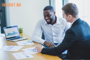 man smiling as client points towards charts on paper